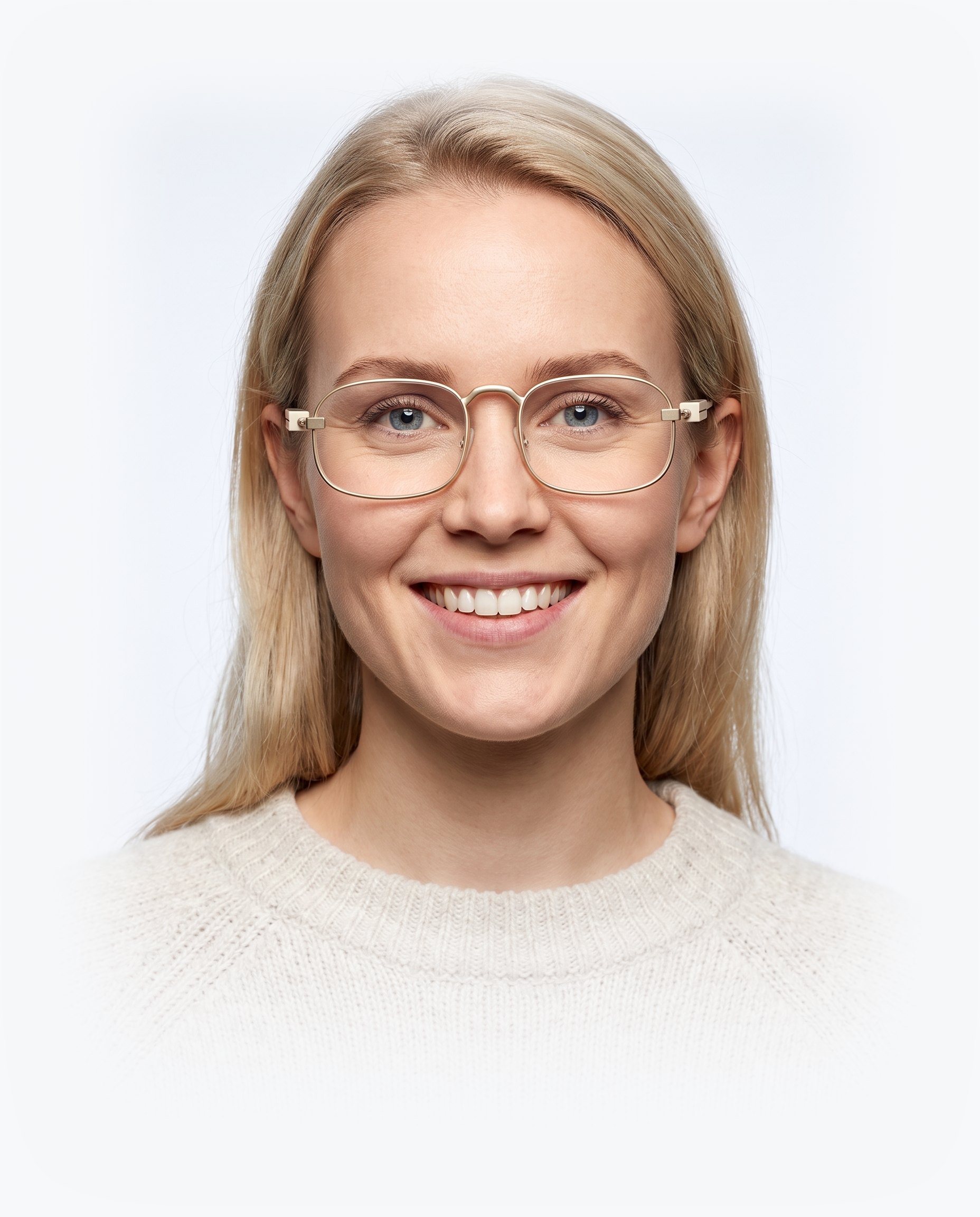 A woman wearing the Snow frame: a thin champagne-gold wire rim with clear lenses, seen straight on against a plain studio backdrop.